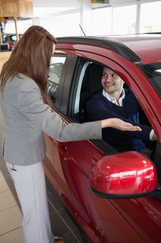 Businesswoman presenting the car to a client in a dealership