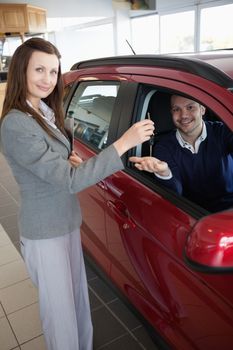 Man tending his hand while receiving car keys in adealership