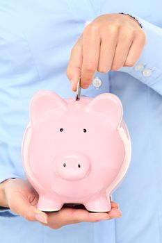 Piggybank money concept. Savings and financial concept closeup of business woman hand putting money in piggy bank savings.