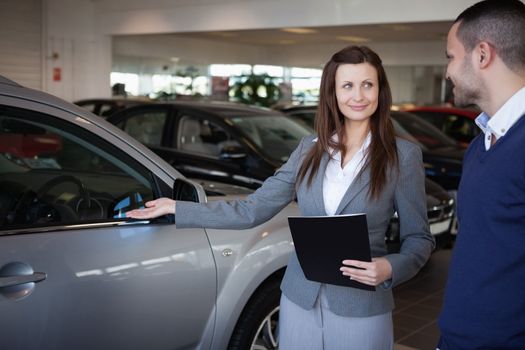 Woman presenting something to a man in a dealership