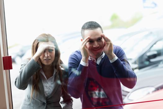 People looking through a shopwindow of a dealership