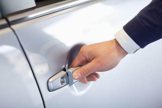Close up of a man opening a car door in a garage