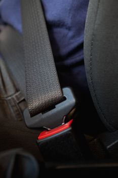 Person being seated with fastened seatbelt in a car