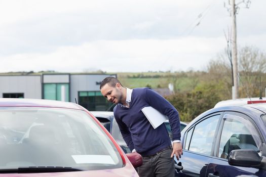 Man looking at a car while leaning outdoors