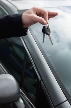Someone holding car keys by his fingertips outdoors