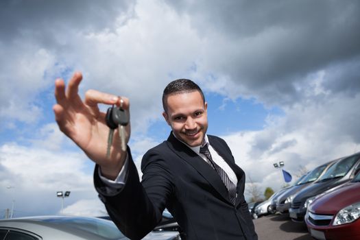 Happy seller holding car keys outdoors