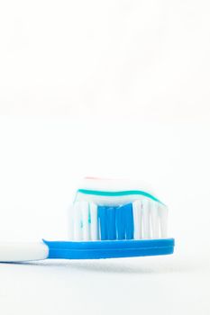 Toothpaste on a toothbrush against white background
