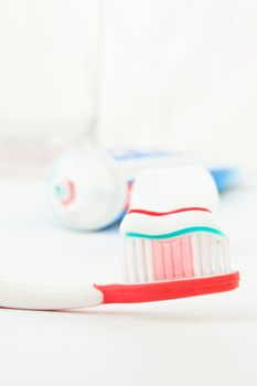 Tube of toothpaste next to a toothbrush against white background