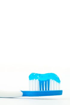 Blue toothpaste on a toothbrush against white background