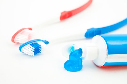 Two toothbrushes next to a tube of toothpaste against white background