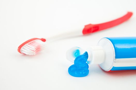 Tube of toothpaste with blue toothpaste against white background