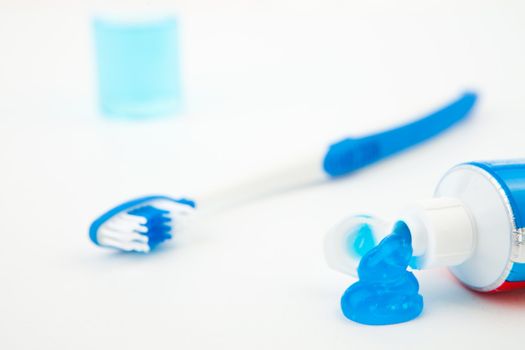 Close up of a toothbrush next to a tube of toothpaste against white background