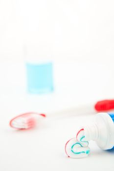 Red toothbrush next to a glass against white background