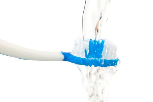 Close up of water flowing on a toothbrush against white background