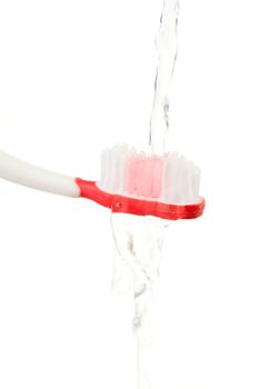 Water flowing on a red toothbrush against white background