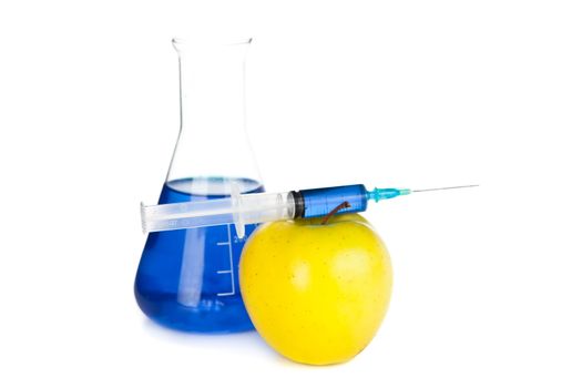 Syringe on an apple next to a beaker against a white bakground
