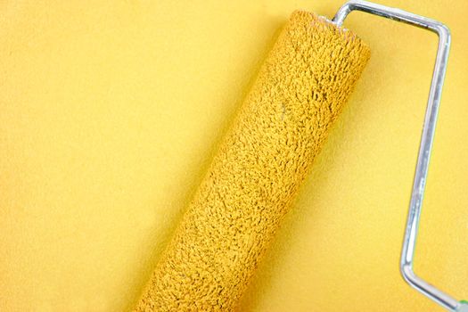 Yellow background with a paint roller in the middle