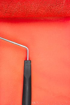 Red paint roller with handle on a background