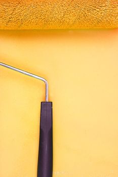 Yellow paint roller with handle on a background