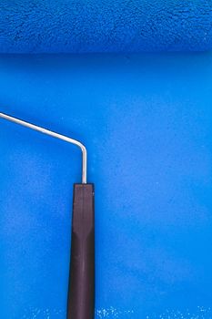 Blue paint roller with handle on a background