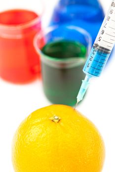 Syringe pricking a lemon against a white background