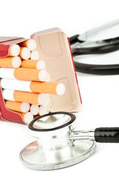 Cigarette pack next to a stethoscope against a white background