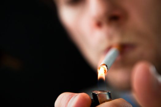 Man lighting a cigarette against a black background