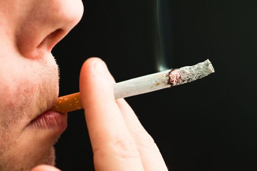Man smoking a cigarette against a black background