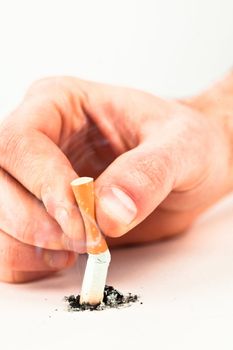 Hand crushing a cigarette against a white background