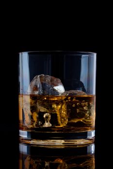 Glass with whiskey against a black background