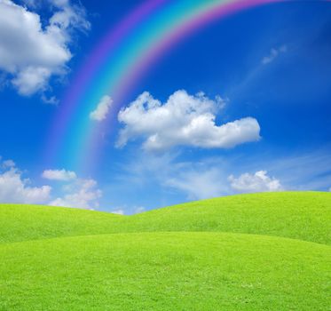 Green field with blue sky and rainbow