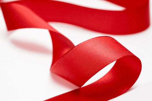 Shiny red satin ribbon on white background