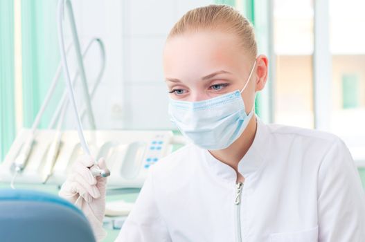 female dentists in protective mask holds a dental drill, the doctors at work