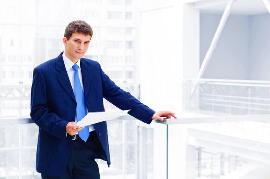 Smiling business man on the balcony, holdings reports