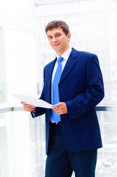 Smiling business man on the balcony, holdings reports