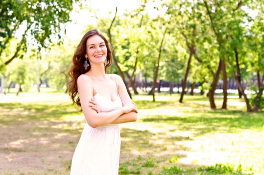 Portrait of an attractive woman in the park, crossed her arms and smile