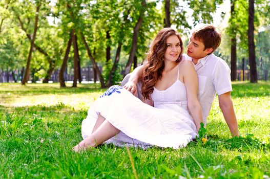 couple in the park sitting on the grass, have a good time together