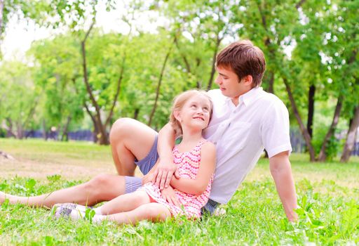 Father and daughter sitting together on the grass, and spend time with family