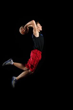 Male basketball player jumping and practicing with a ball