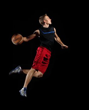 Male basketball player jumping and practicing with a ball