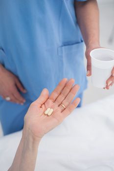 Nurse giving plastic glass to a patient in hospital ward