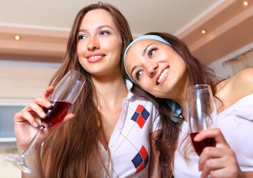 Happy women with glasses of red wine talk about on kitchen