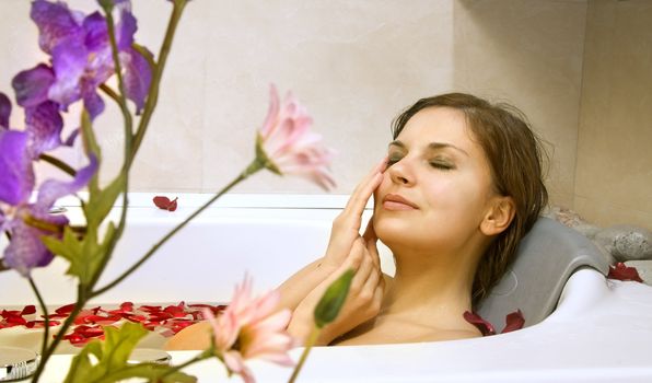 beautiful woman in a bath with petals of rose