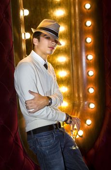 young man with glass of champagne near the mirror in cabaret