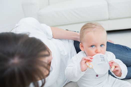 Baby drinking a bottle of water in living room