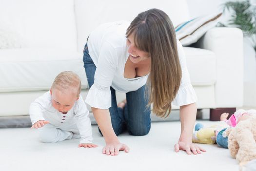 Mother on all fours next to a baby in living room