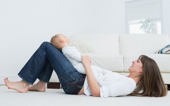 Mother lying on the floor with a baby in living room