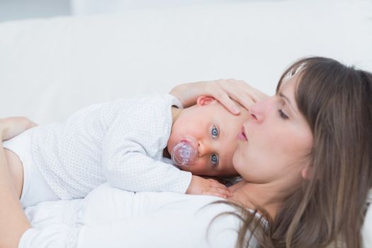 Baby lying on his mother in living room