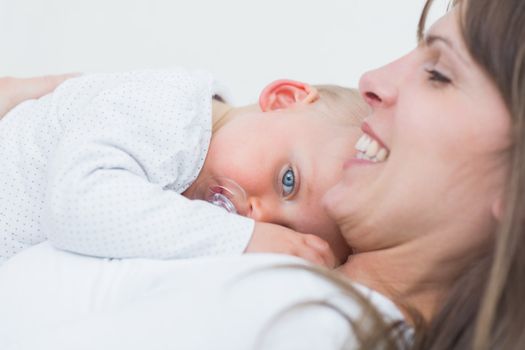 Baby lying on the chest of his mother in living room