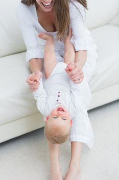 Mother sitting on a sofa playing with a baby in living room